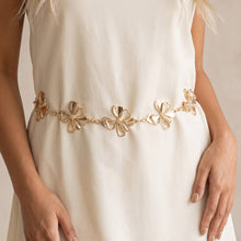 Load image into Gallery viewer, A gold-tone waist chain featuring delicate flower-shaped details, worn over a white dress.