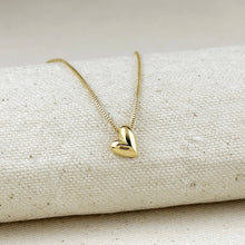 Load image into Gallery viewer, Gold heart-shaped necklace on a textured beige surface