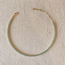 Load image into Gallery viewer, Gold bracelet with green beads on a beige fabric background