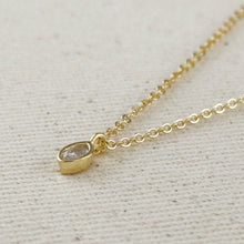 Load image into Gallery viewer, Gold necklace with a small diamond pendant on a light beige fabric background