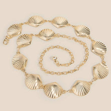 Load image into Gallery viewer, A gold tone chain belt featuring repeating seashell-shaped links and an adjustable chain extender, displayed on a white background.