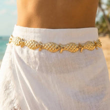 Load image into Gallery viewer, A gold-tone waist chain featuring repeating textured fish, worn over a white skirt.
