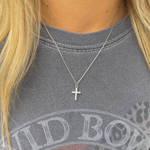 Load image into Gallery viewer, Silver cross necklace on a person wearing a gray sweatshirt with visible branding.