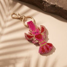Load image into Gallery viewer, Pin and red lobster beaded key chain with a beige background and a brown rock 
