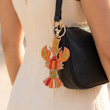 Load image into Gallery viewer, Bright and colorful crawfish keychain on a black purse with a woman in beige holding the purse under her arm 
