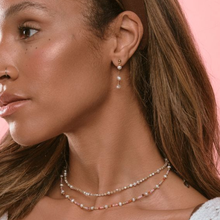 Load image into Gallery viewer, Close-up of a woman wearing pearl drop earrings and necklaces against a pink background

