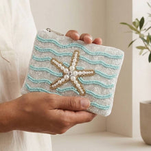 Load image into Gallery viewer, A beaded coin purse with a pearl starfish on it.  A person with a white outfit is holding it
