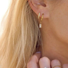 Load image into Gallery viewer, Close-up of a person wearing gold hoop earrings with a blurred background
