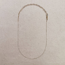 Load image into Gallery viewer, Gold chain necklace on a beige textured background
