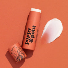 Load image into Gallery viewer, A peachy orange cosmetic pomegranate and peach lip balm stick with the cap off, placed beside a white cream smear on a matching peach background. The stick reads 'poppy &amp; pout'
