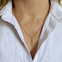 Load image into Gallery viewer, Gold necklace with a cross pendant worn by a person in a white shirt.
