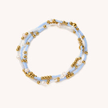 Load image into Gallery viewer, Multistrand bracelet with gold beads and light blue and white strands on a white background
